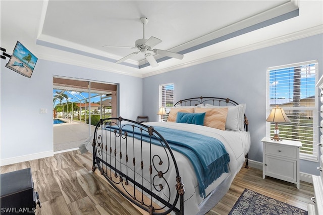 bedroom featuring ceiling fan, access to exterior, a raised ceiling, and multiple windows