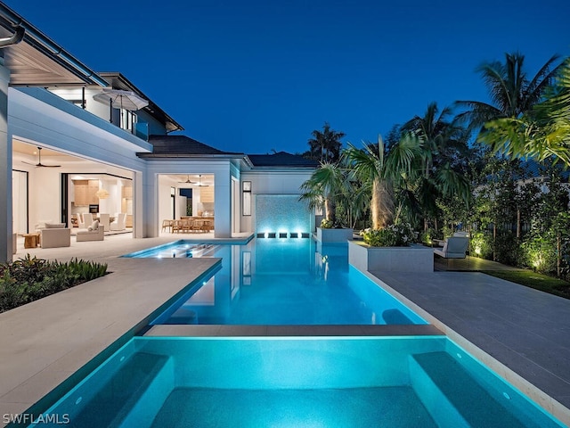 pool at twilight with an in ground hot tub and a patio area