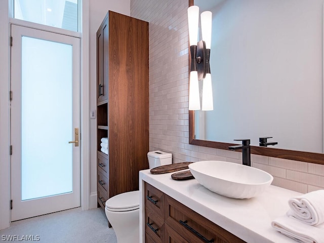 bathroom with vanity, toilet, decorative backsplash, and a wealth of natural light