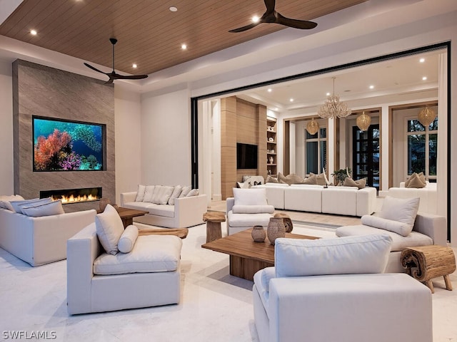 cinema room with a premium fireplace, a raised ceiling, wood ceiling, and a chandelier