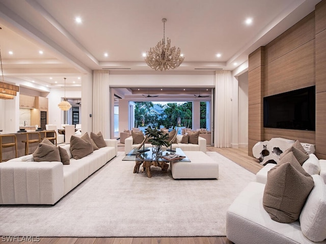 living room with ceiling fan with notable chandelier and light hardwood / wood-style floors