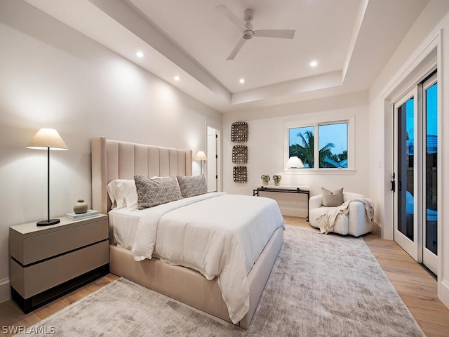 bedroom featuring a raised ceiling, access to outside, light hardwood / wood-style flooring, and ceiling fan