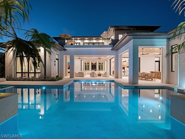 pool at twilight with outdoor lounge area, ceiling fan, and a patio