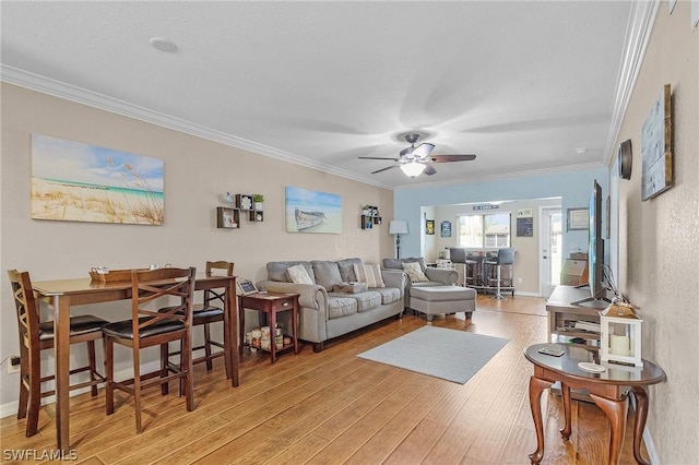 living room featuring ceiling fan, ornamental molding, and light hardwood / wood-style flooring