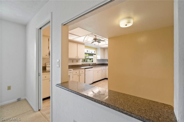 kitchen featuring dishwasher, white cabinets, decorative backsplash, dark stone counters, and ceiling fan