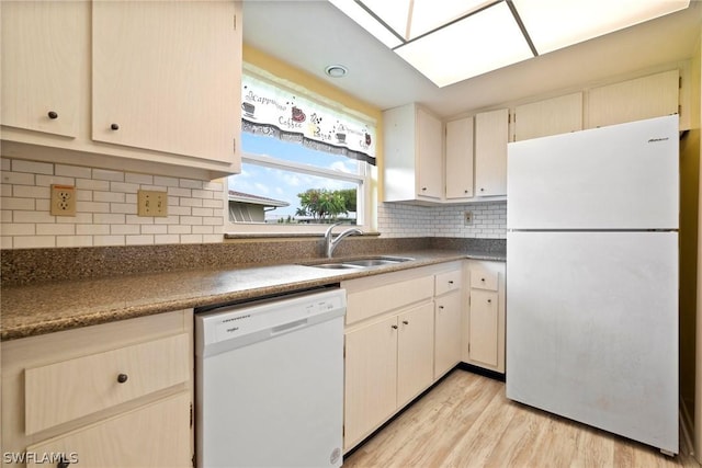 kitchen featuring sink, white appliances, a skylight, light hardwood / wood-style floors, and decorative backsplash