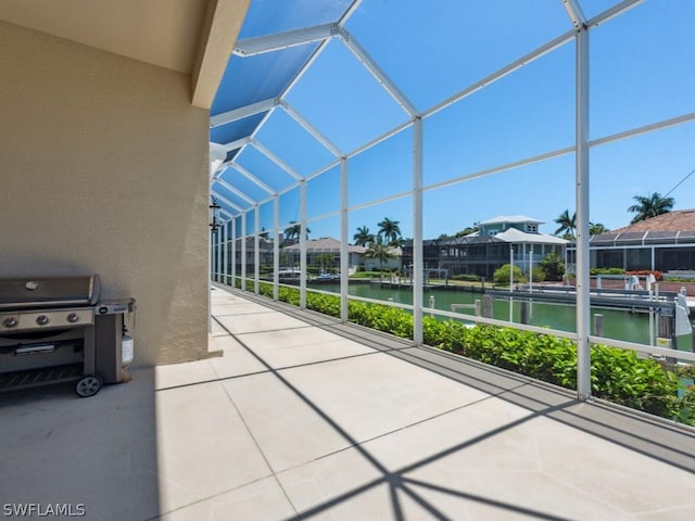 view of patio featuring glass enclosure and a water view