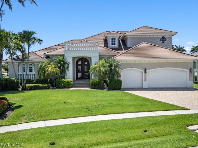 mediterranean / spanish-style home with a front yard, french doors, and a garage