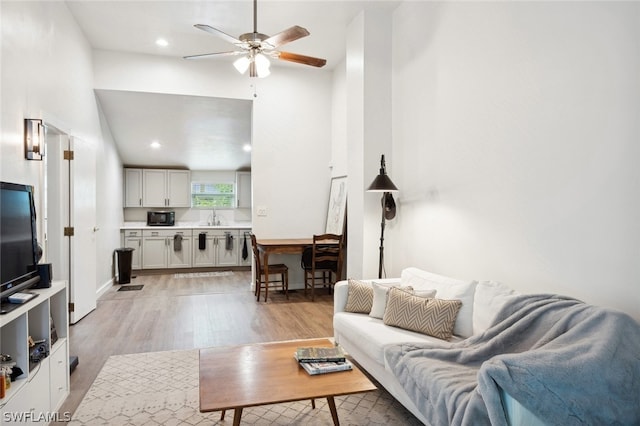 living room with sink, light wood-type flooring, and ceiling fan