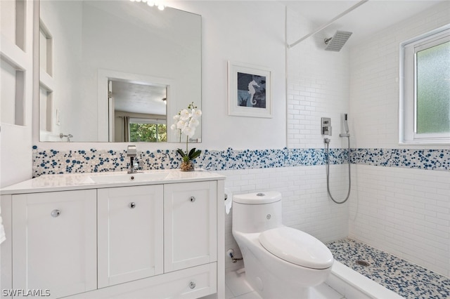 bathroom with tiled shower, vanity, tile walls, toilet, and tile patterned flooring