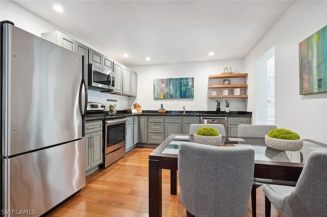 kitchen featuring appliances with stainless steel finishes, light hardwood / wood-style flooring, sink, and gray cabinetry