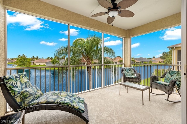 sunroom / solarium featuring a water view, plenty of natural light, and ceiling fan