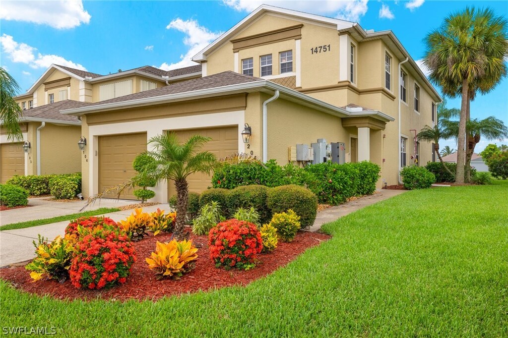 view of front of property with an attached garage, a front lawn, and stucco siding