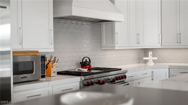 kitchen with white cabinets, decorative backsplash, and premium range hood