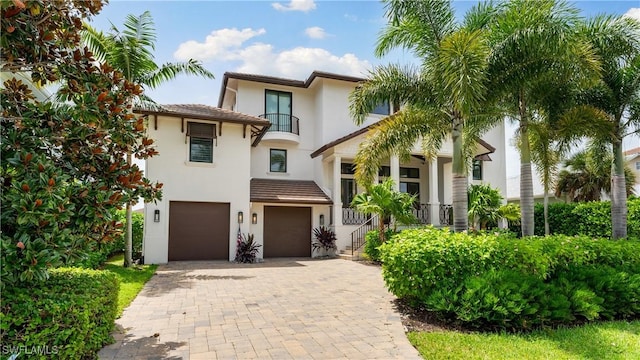 mediterranean / spanish-style house with decorative driveway, an attached garage, and stucco siding