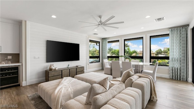 bedroom with beverage cooler, light wood-style flooring, multiple windows, and visible vents