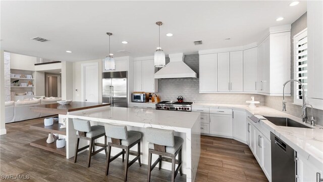 kitchen featuring stainless steel appliances, custom range hood, a sink, and visible vents