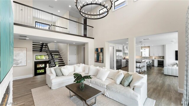 living area featuring stairs, baseboards, wood finished floors, and a notable chandelier