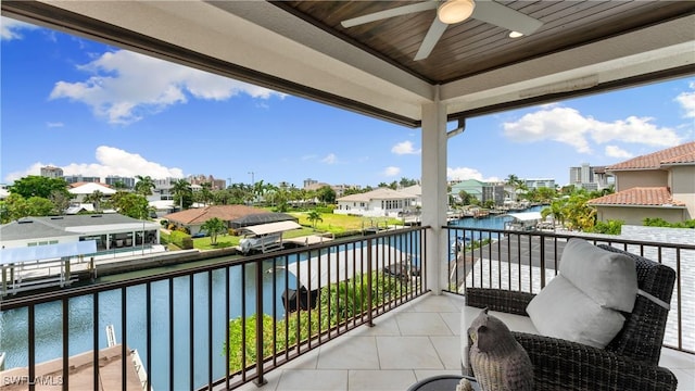 balcony with a residential view, a water view, and ceiling fan