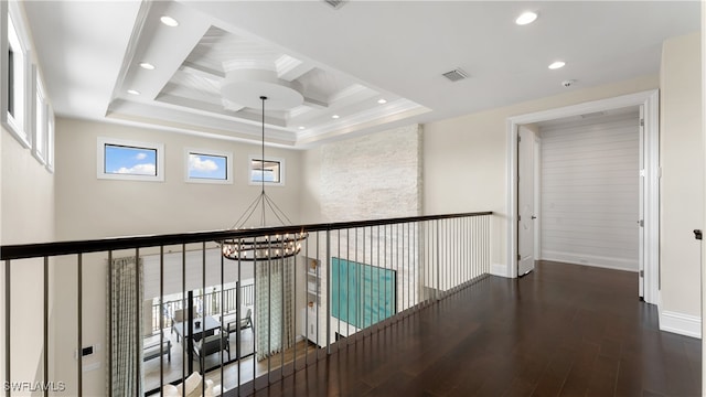 hallway featuring coffered ceiling, an inviting chandelier, beamed ceiling, dark hardwood / wood-style floors, and ornamental molding