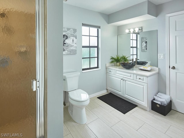 full bath with a shower with shower door, baseboards, toilet, and vanity