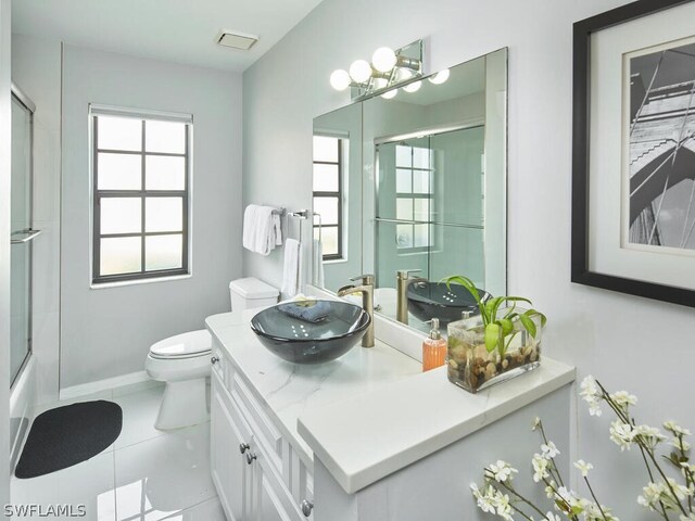 full bathroom featuring tile patterned floors, vanity, toilet, and bath / shower combo with glass door