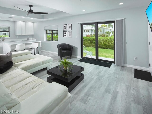 living room with light wood-type flooring, sink, a wealth of natural light, and ceiling fan