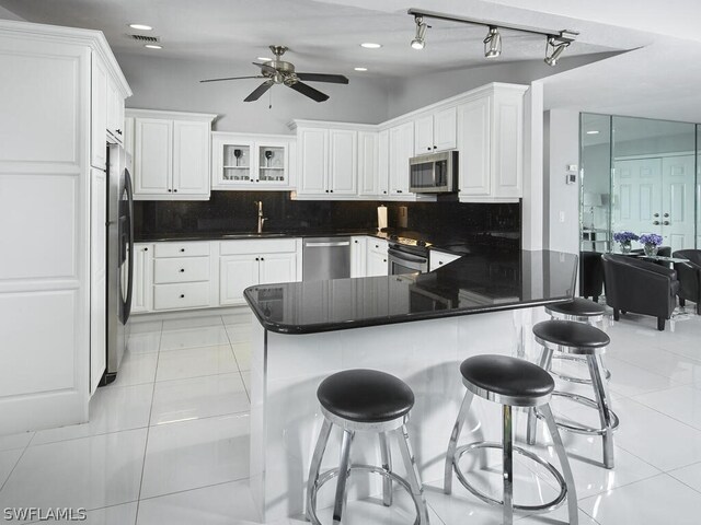 kitchen featuring kitchen peninsula, white cabinetry, sink, and appliances with stainless steel finishes