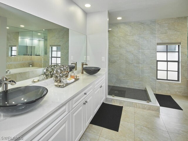 bathroom with tile patterned flooring, a tile shower, and vanity