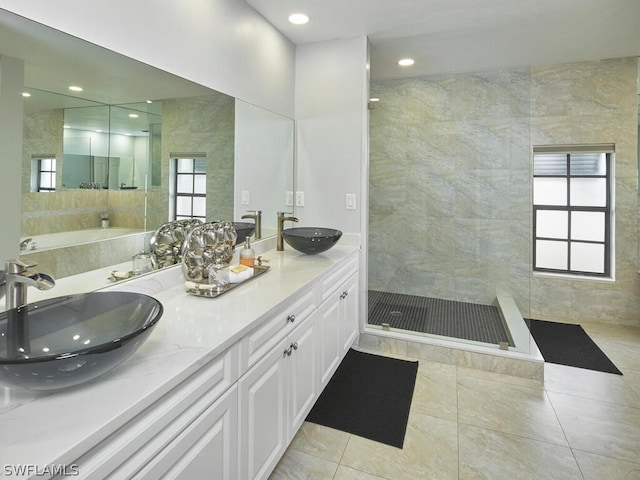 bathroom featuring a wealth of natural light, tiled shower, and a sink