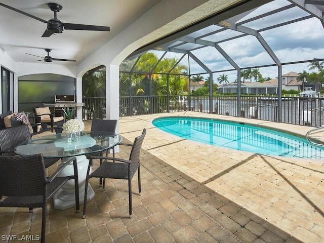 view of swimming pool with a lanai, ceiling fan, a water view, and a patio