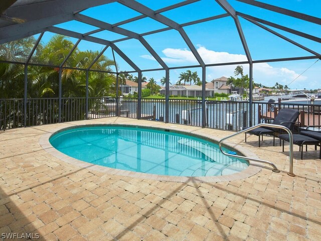 view of pool with glass enclosure, a water view, and a patio