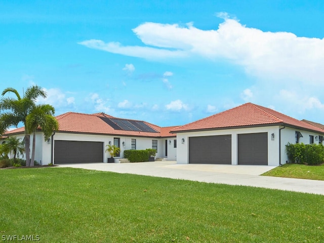 view of front facade featuring a tiled roof, solar panels, an attached garage, and a front yard