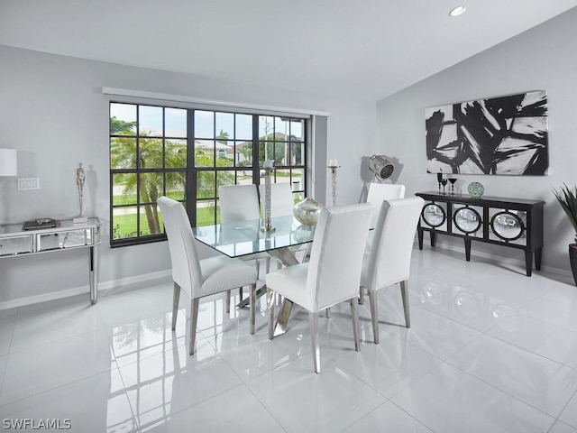 tiled dining space featuring vaulted ceiling