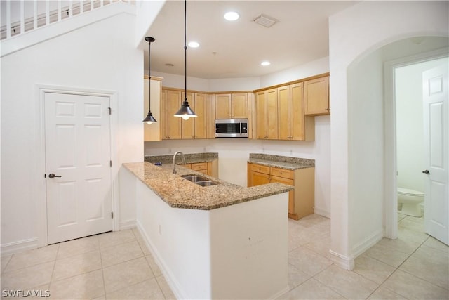 kitchen featuring light stone countertops, sink, hanging light fixtures, kitchen peninsula, and light tile patterned floors