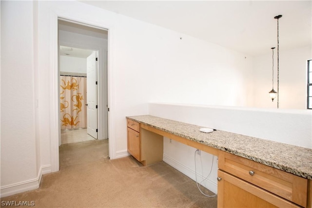 unfurnished office featuring built in desk and light colored carpet