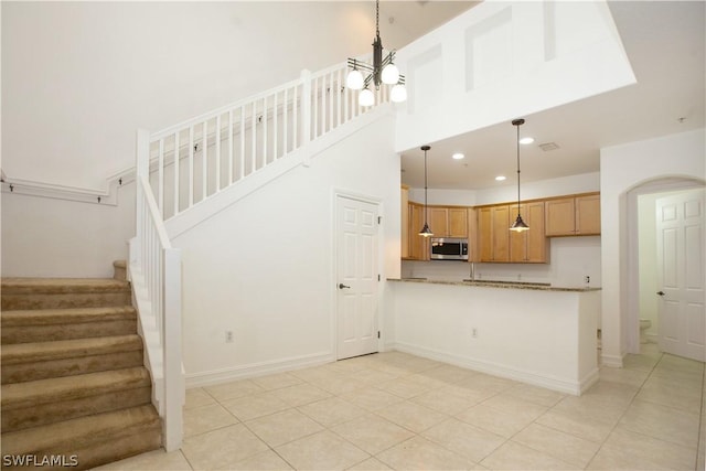 kitchen with kitchen peninsula, a notable chandelier, stone counters, hanging light fixtures, and light tile patterned flooring