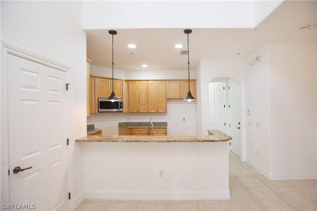 kitchen with pendant lighting, light tile patterned floors, light brown cabinetry, light stone counters, and kitchen peninsula