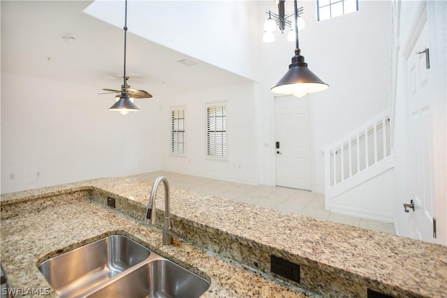 kitchen featuring light stone countertops, ceiling fan, sink, pendant lighting, and light tile patterned floors