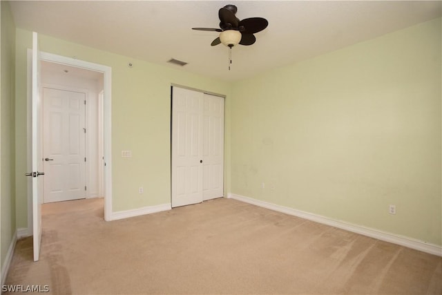 unfurnished bedroom with a closet, light colored carpet, and ceiling fan