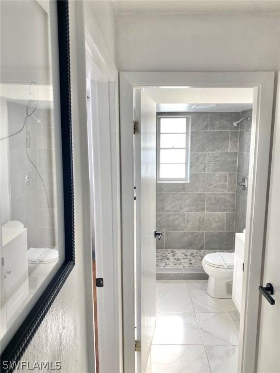 bathroom with tiled shower, vanity, and toilet