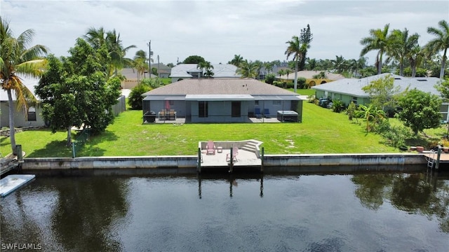 back of property with a water view, a yard, and a patio area