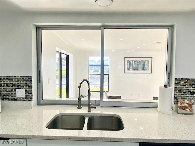 kitchen with tasteful backsplash, sink, and light stone countertops