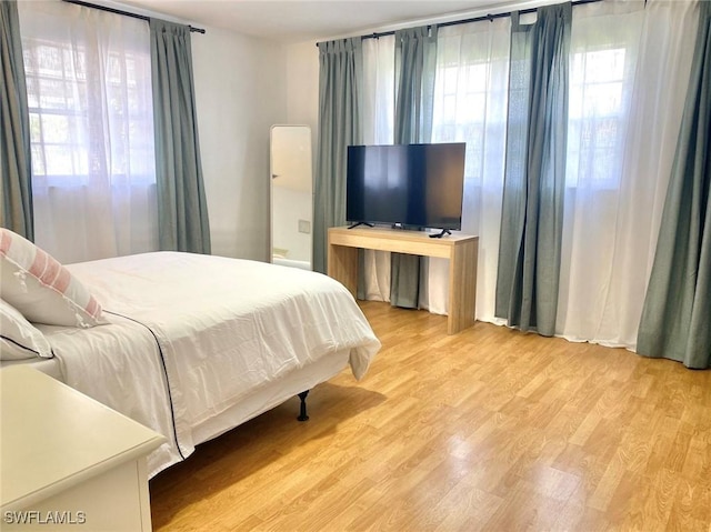 bedroom with multiple windows and wood finished floors