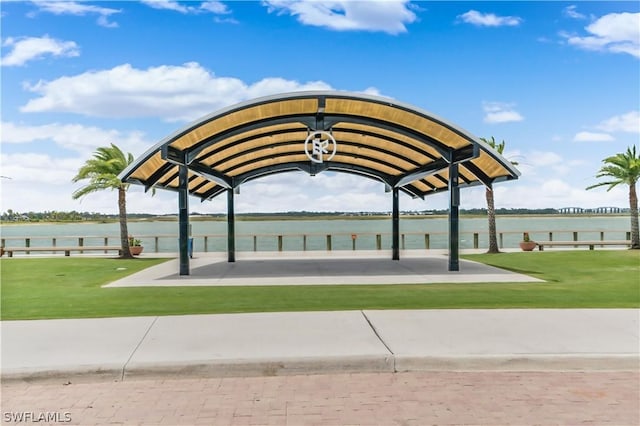 view of property's community with a water view and a lawn