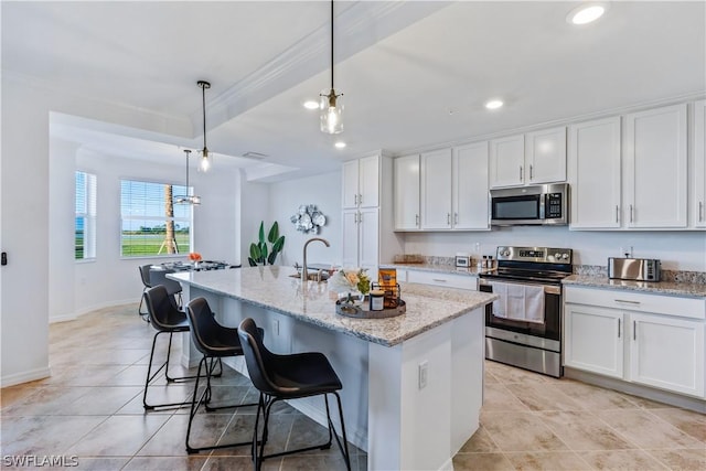 kitchen with stainless steel appliances, white cabinetry, an island with sink, and pendant lighting