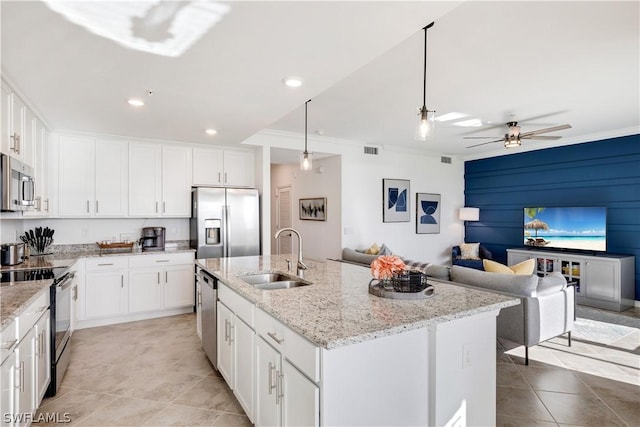 kitchen with an island with sink, hanging light fixtures, sink, appliances with stainless steel finishes, and white cabinets