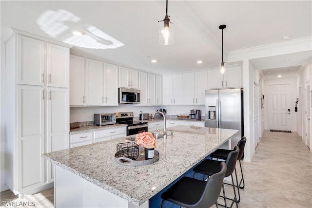 kitchen featuring appliances with stainless steel finishes, an island with sink, light stone counters, sink, and white cabinetry