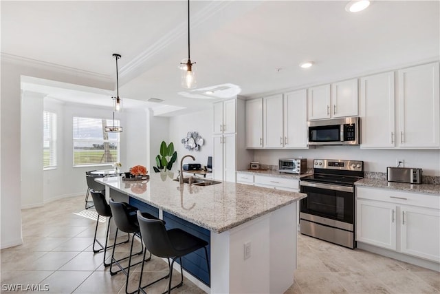 kitchen featuring a center island with sink, appliances with stainless steel finishes, white cabinets, and decorative light fixtures