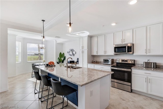 43030 Greenway Blvd Unit 412, Punta Gorda, FL 33982 - kitchen featuring stainless steel appliances, a sink, white cabinetry, ornamental molding, and an island with sink